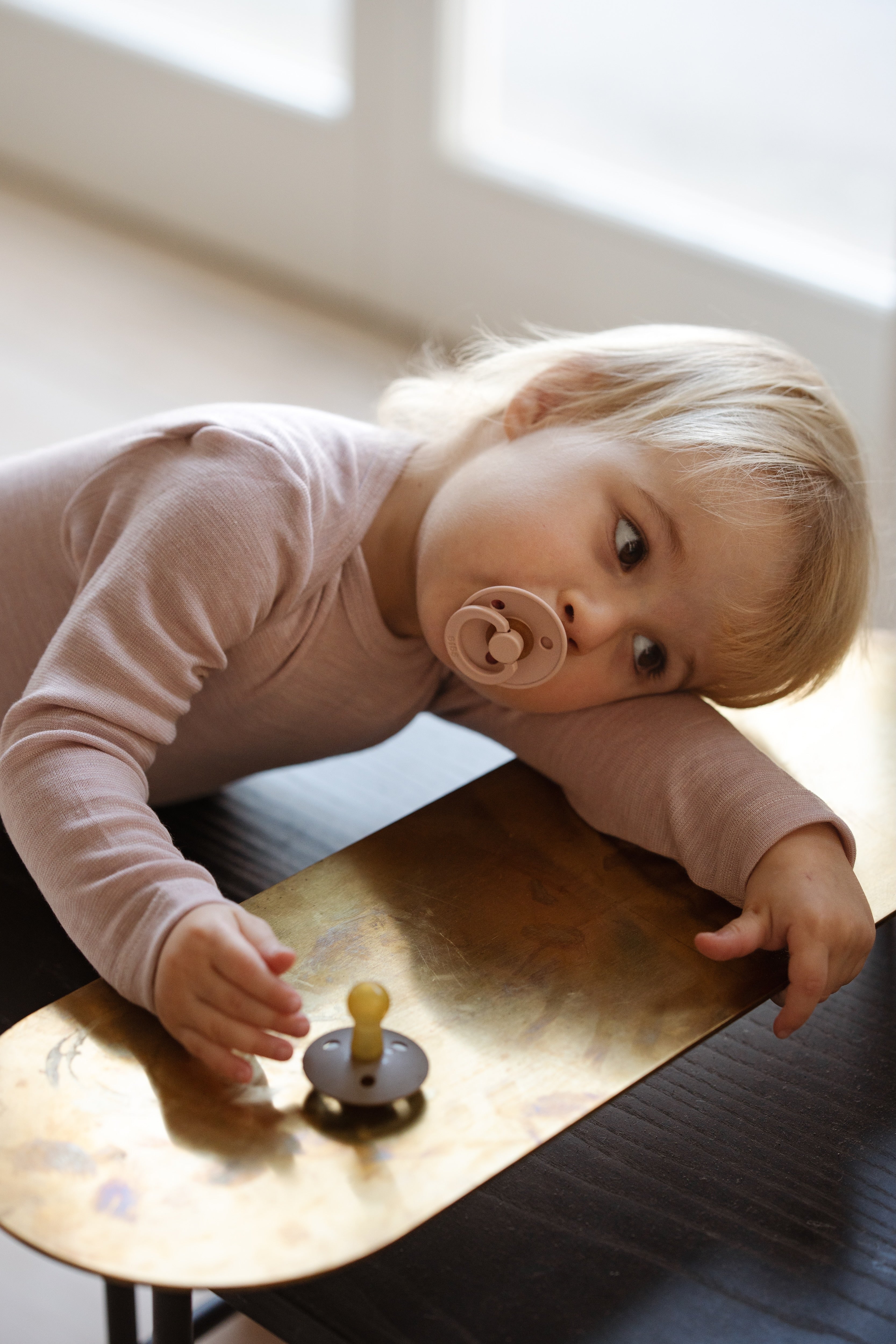 Toddler wearing wool-silk essentials jersey set (body and leggins) in rose color, eating an apple